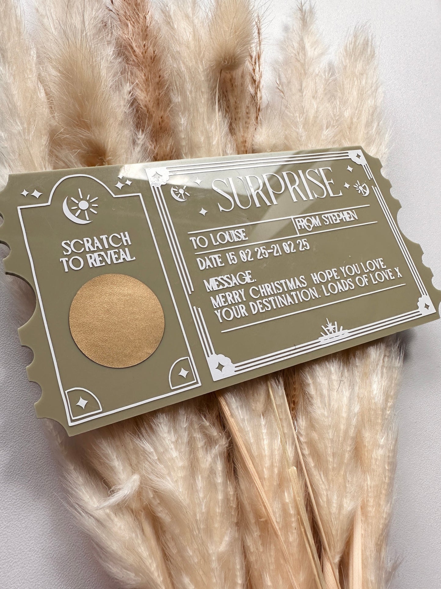 A personalised acrylic scratch-to-reveal ticket with an elegant vintage-inspired design, featuring engraved text and a gold scratch-off area. The text includes customisable sections for recipient names, date, and a special message, making it perfect for surprise trip announcements, concert reveals, or gift experiences. The acrylic has a modern, sleek finish with white vinyl lettering on a forest green acrylic ticket shape enhancing its luxurious look.