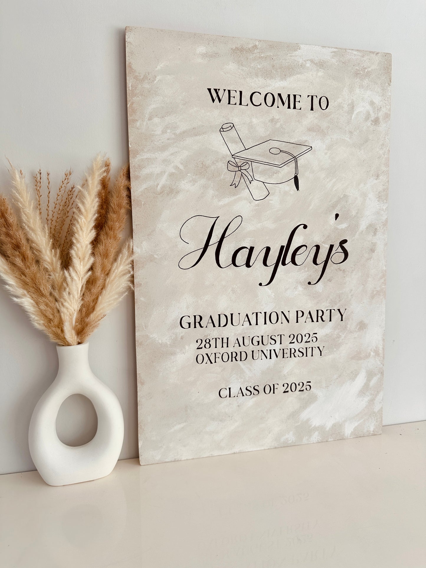 Graduation party invitation sign with decorative elements on a neutral background