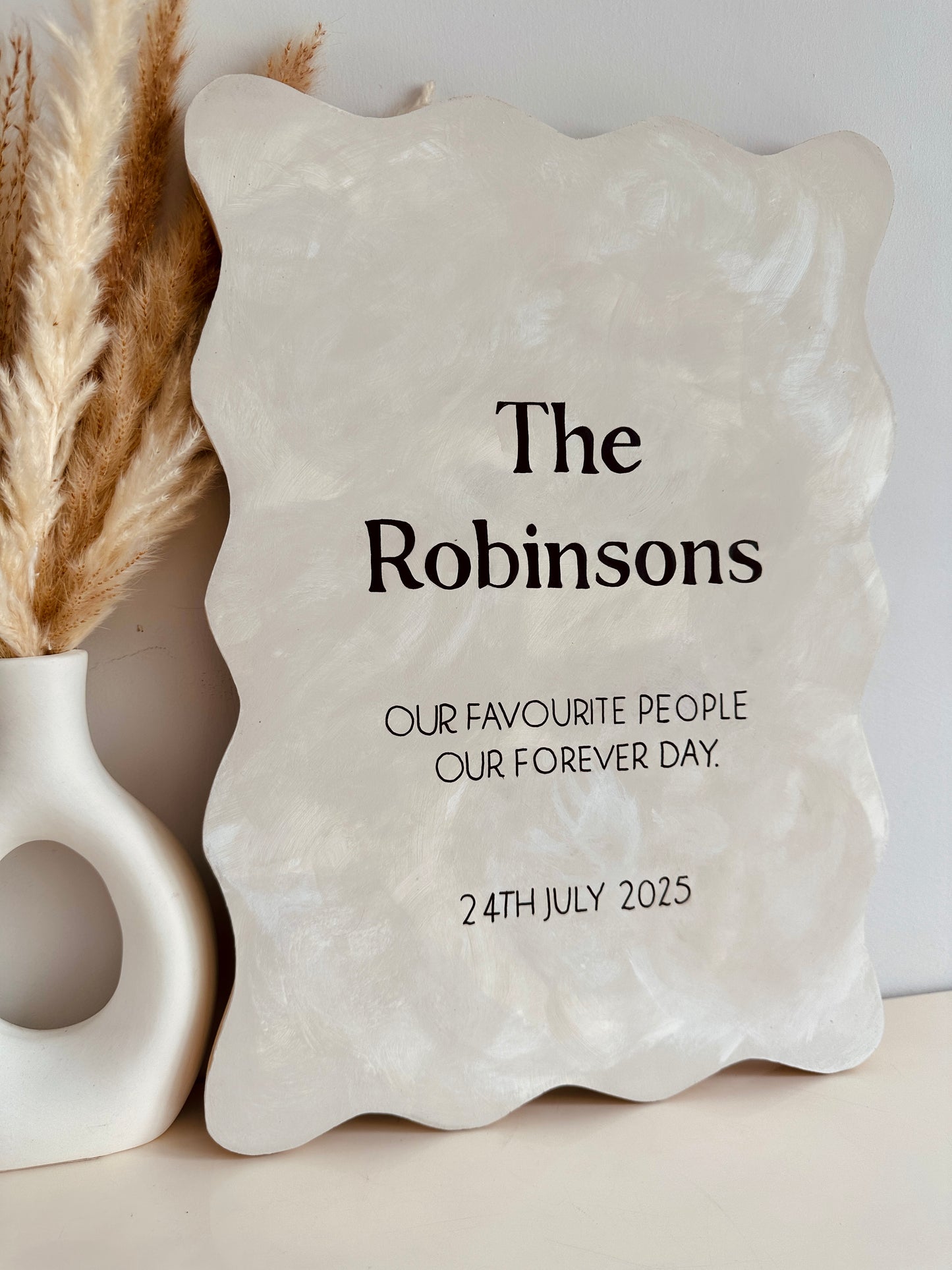 Personalised rustic wooden sign with surname and wedding date. Decorative stone plaque with 'The Robinsons' text and personalised message on a neutral background.