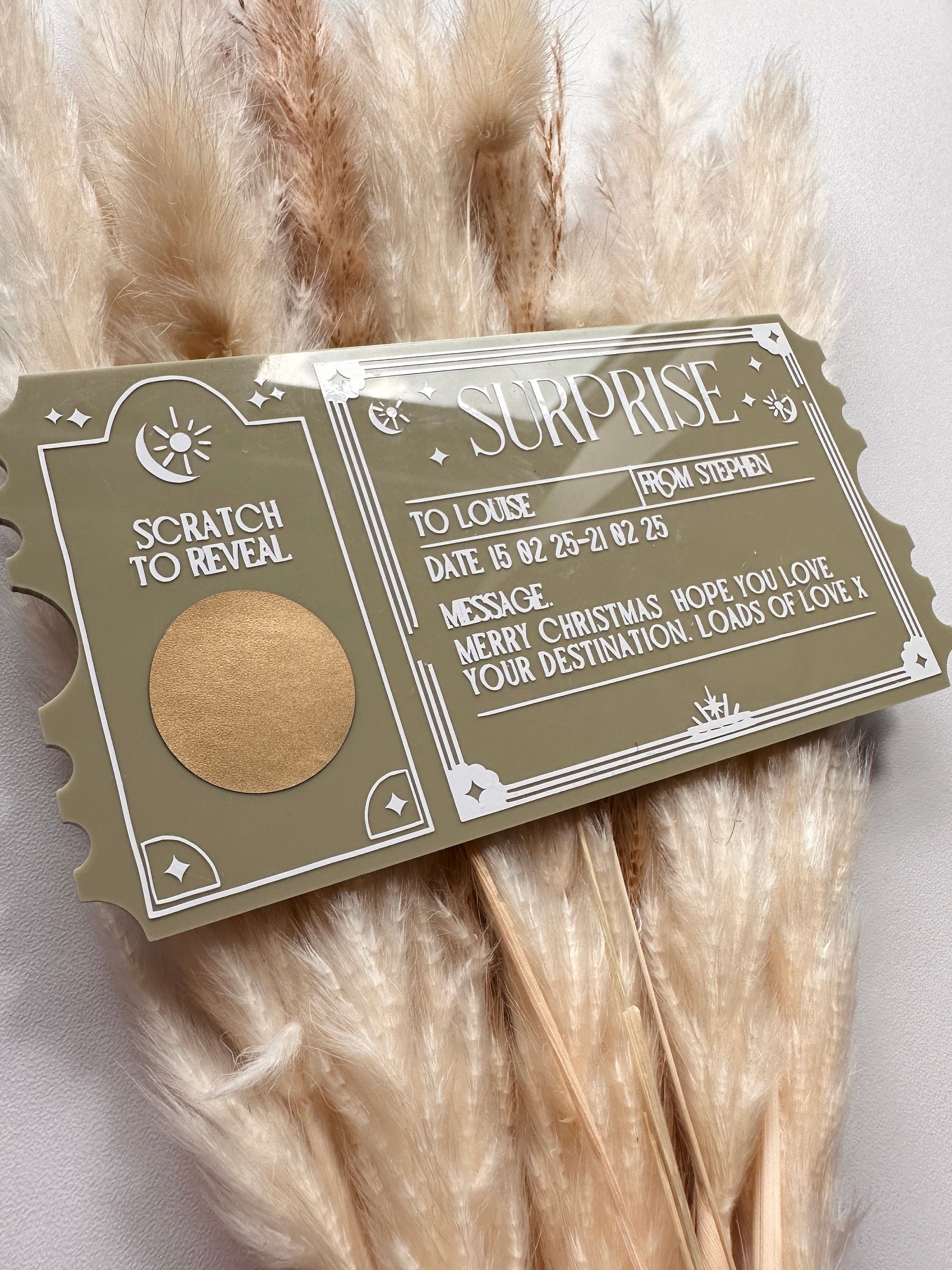 A personalised acrylic scratch-to-reveal ticket with an elegant vintage-inspired design, featuring engraved text and a gold scratch-off area. The text includes customisable sections for recipient names, date, and a special message, making it perfect for surprise trip announcements, concert reveals, or gift experiences. The acrylic has a modern, sleek finish with white vinyl lettering on a forest green acrylic ticket shape enhancing its luxurious look.