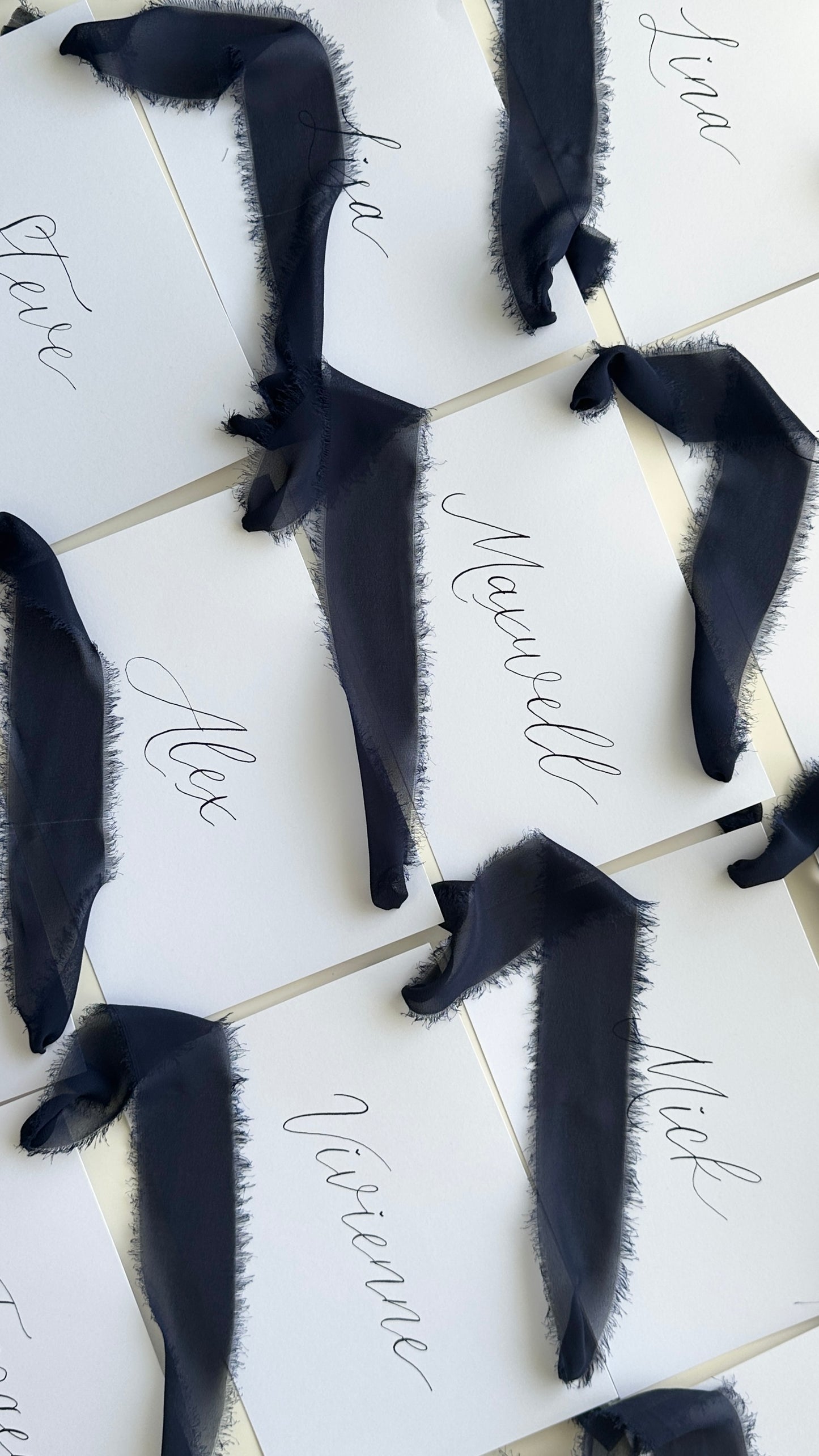 handwritten names written in black in on white 5 card finished with navy blue chiffon ribbon