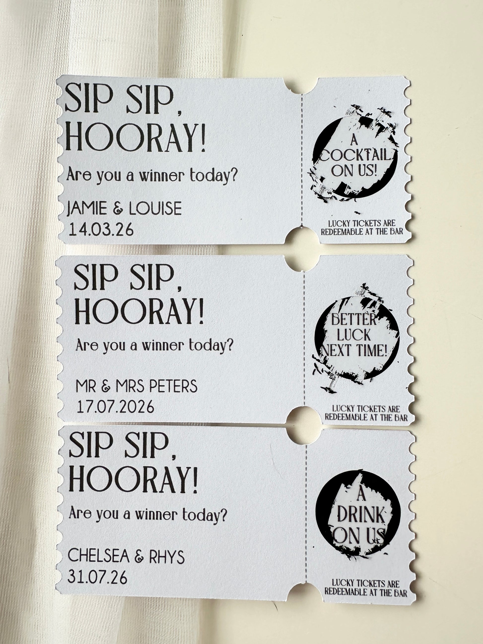 Set of three personalised tickets with black scratch ticket scratched off to reveal winning or loosing tickets with names and dates on a white background