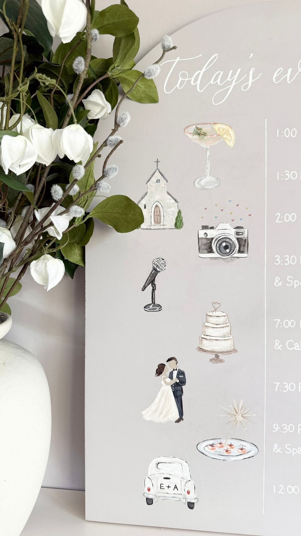 A close up of our A3 wooden arch sign with background colour in mushroom taupe, this sign features handwritten white lettering with the title Today’s events and each stage of your day written in a horizontal line with hand-painted illustrations next to each special moment