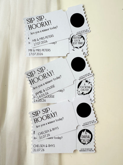 Set of three personalised tickets with black scratch ticket scratched off to reveal winning or loosing tickets next to an example ticket of sticker not yet scratched with names and dates on a white background