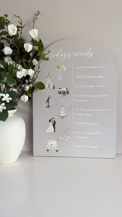 A3 wooden arch sign with background colour in mushroom taupe, this sign features handwritten white lettering with the title Today’s events and each stage of your day written in a horizontal line with hand-painted illustrations next to each special moment