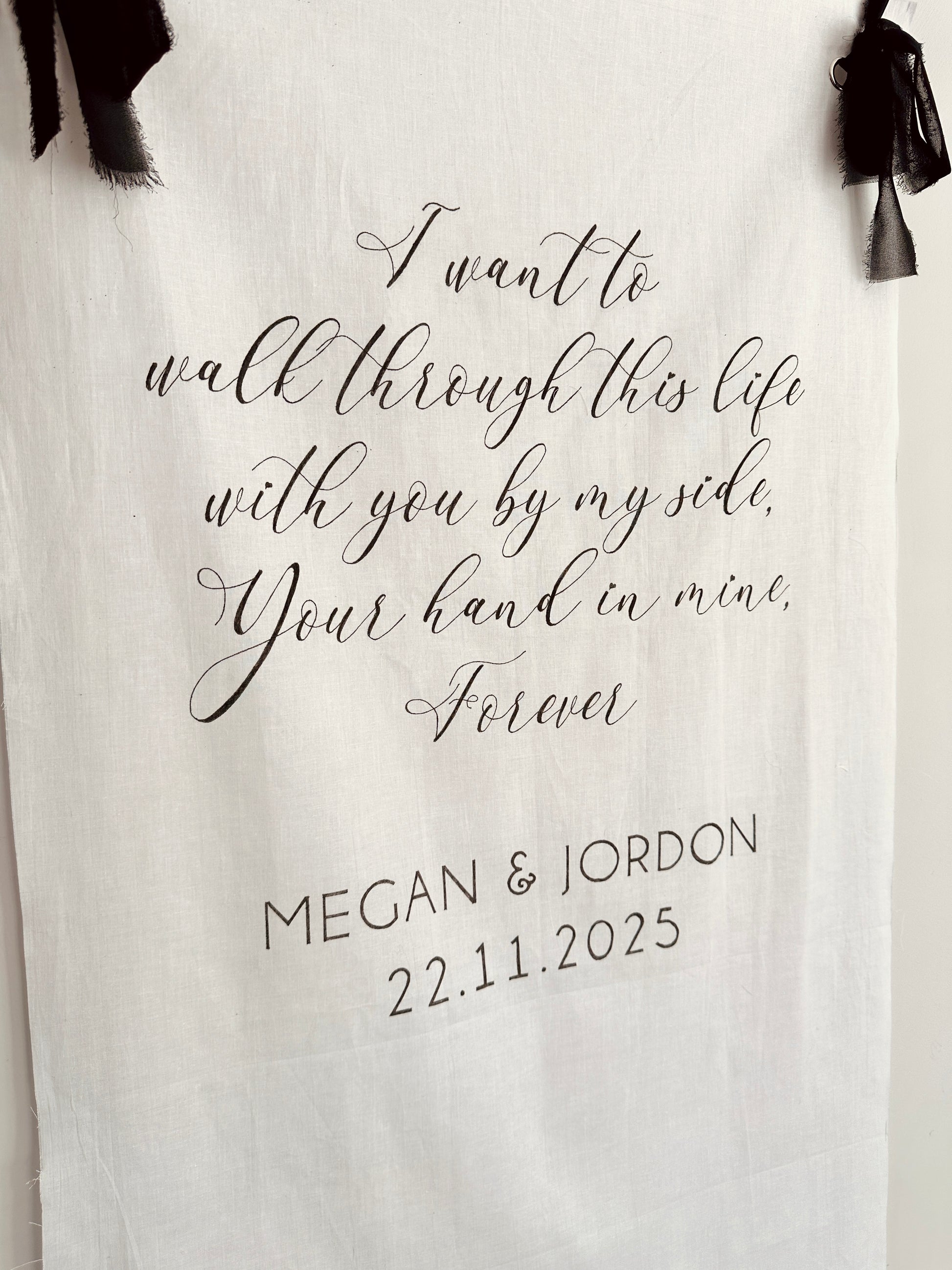 White linen wedding sign with chiffon black ribbon to hang sign, with black text and names handwritten on