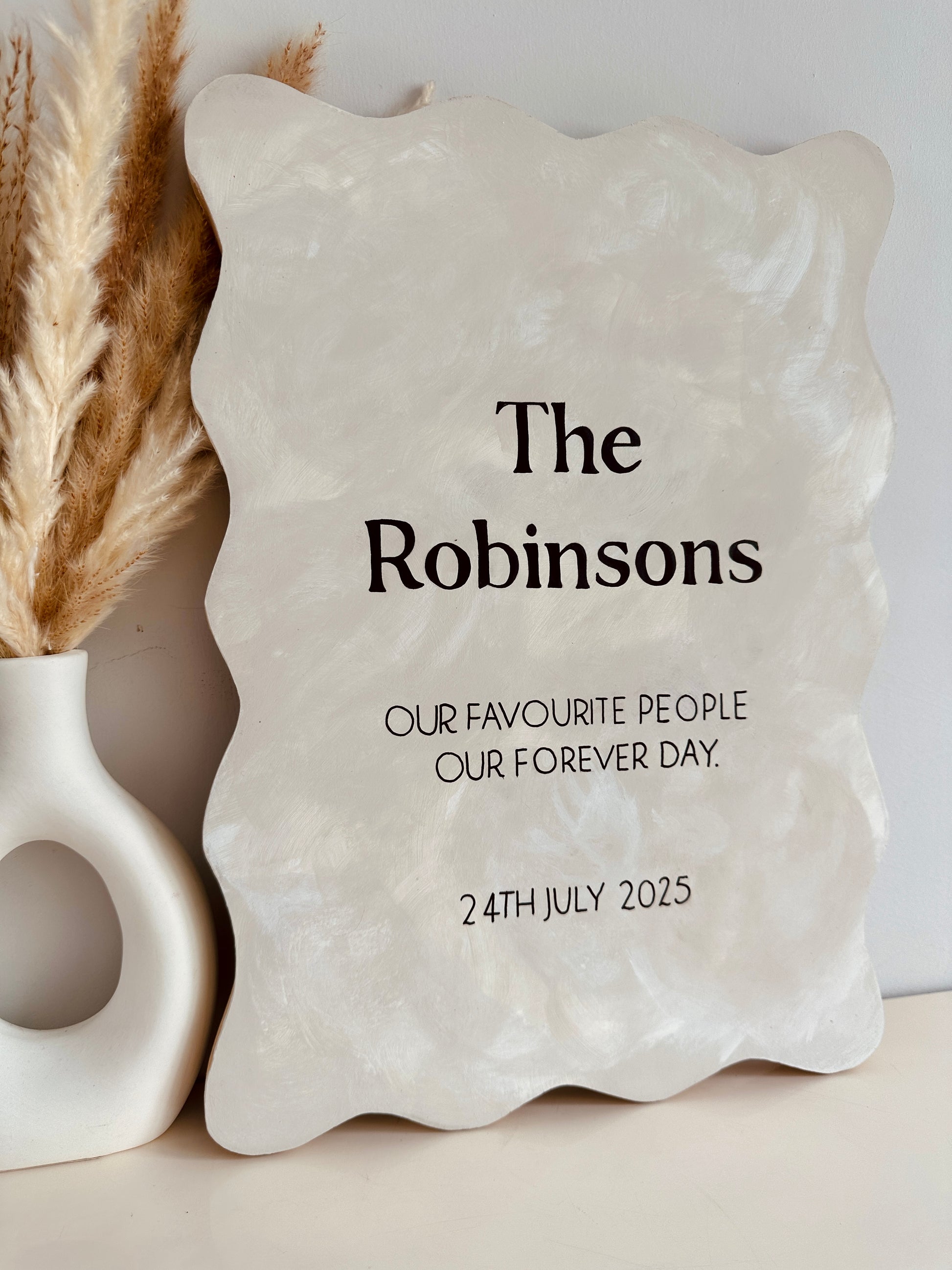 Personalised rustic wooden sign with surname and wedding date. Decorative stone plaque with 'The Robinsons' text and personalised message on a neutral background.